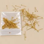 Gold-colored metal jump ring findings with straight pins and small loops, shown both inside a clear plastic bag and scattered on a beige background.